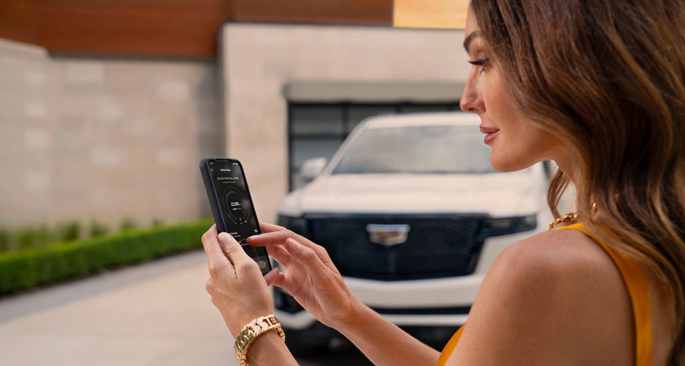 lady checking her mobile with a Cadillac vehicle background | Marvin K. Brown Cadillac in San Diego CA